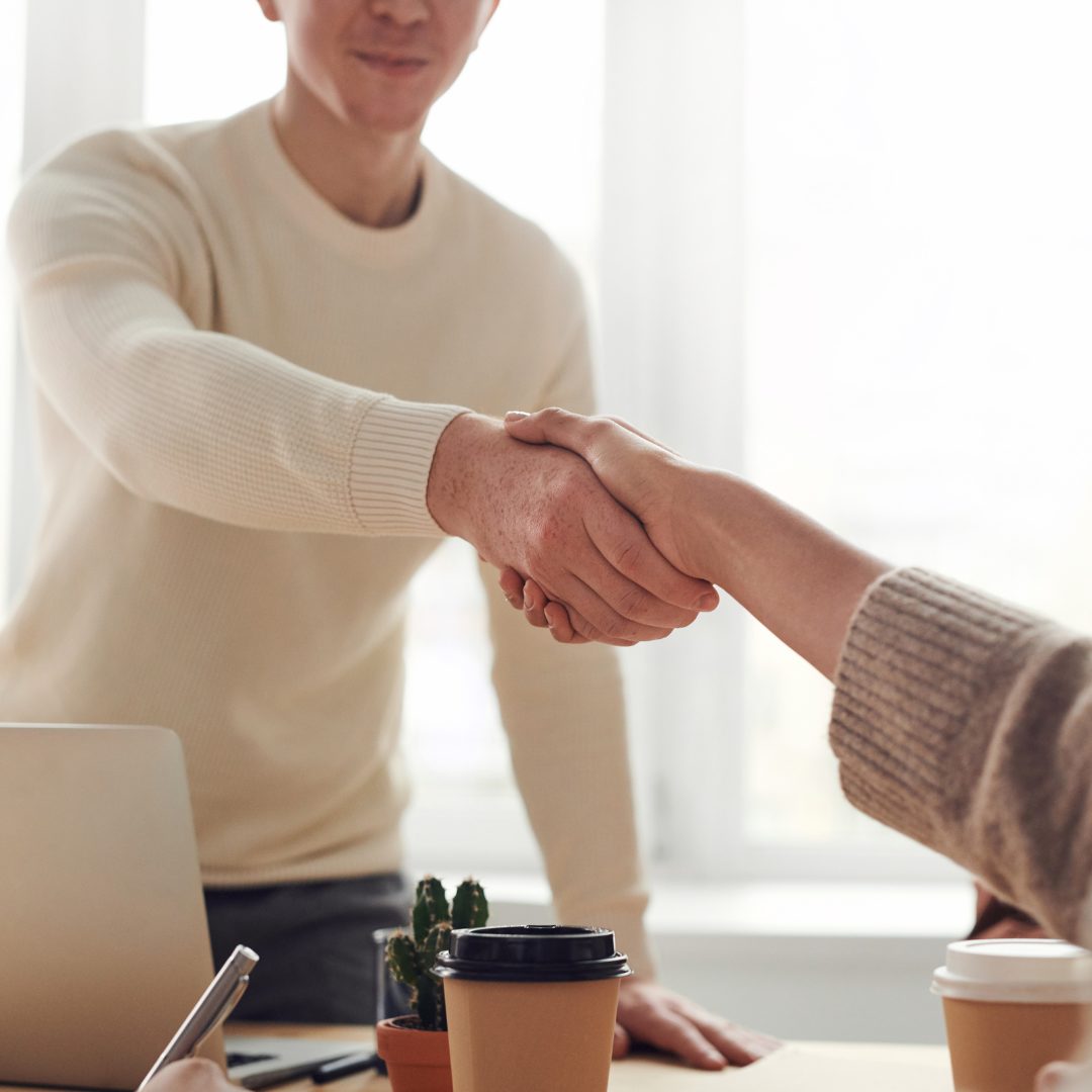 Deux personnes se serrant la main dans un environnement professionnel, symbolisant la collaboration et la confiance chez Aquarelle service.